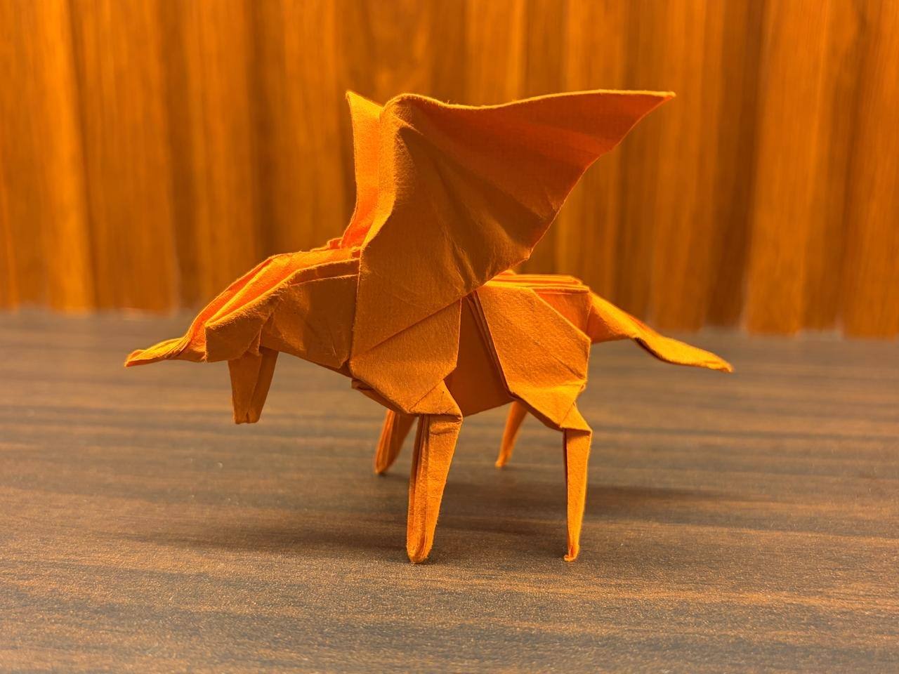 The orange paper Pegasus side on, wings swept up and its tail stretching out behind.